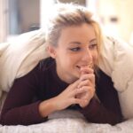 view-beautiful-caucasian-female-looking-away-smiling-white-blanket_181624-33335